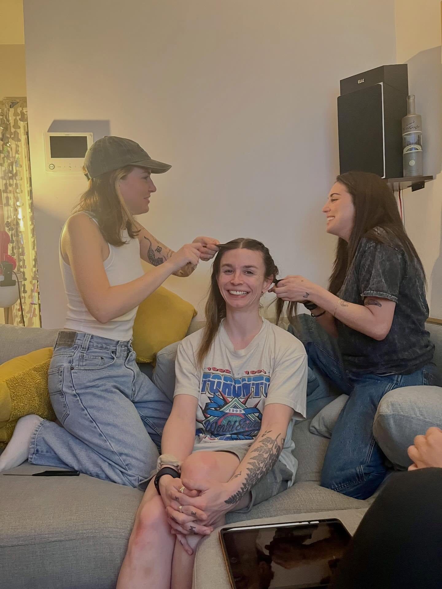 Friends helping Grace get ready while she sits smiling.