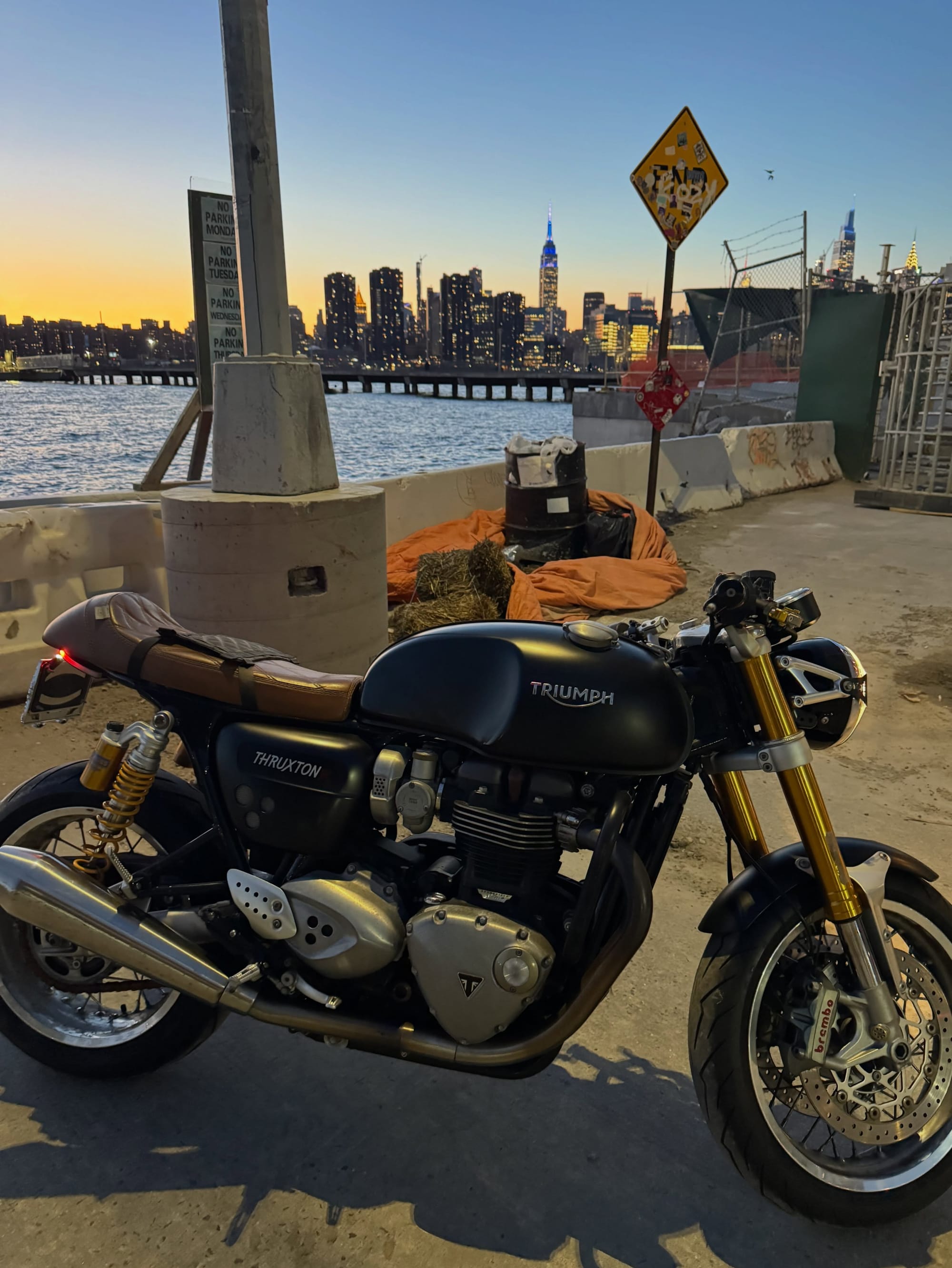 The Triumph parked beside the waterfront, with the city skyline beyond.