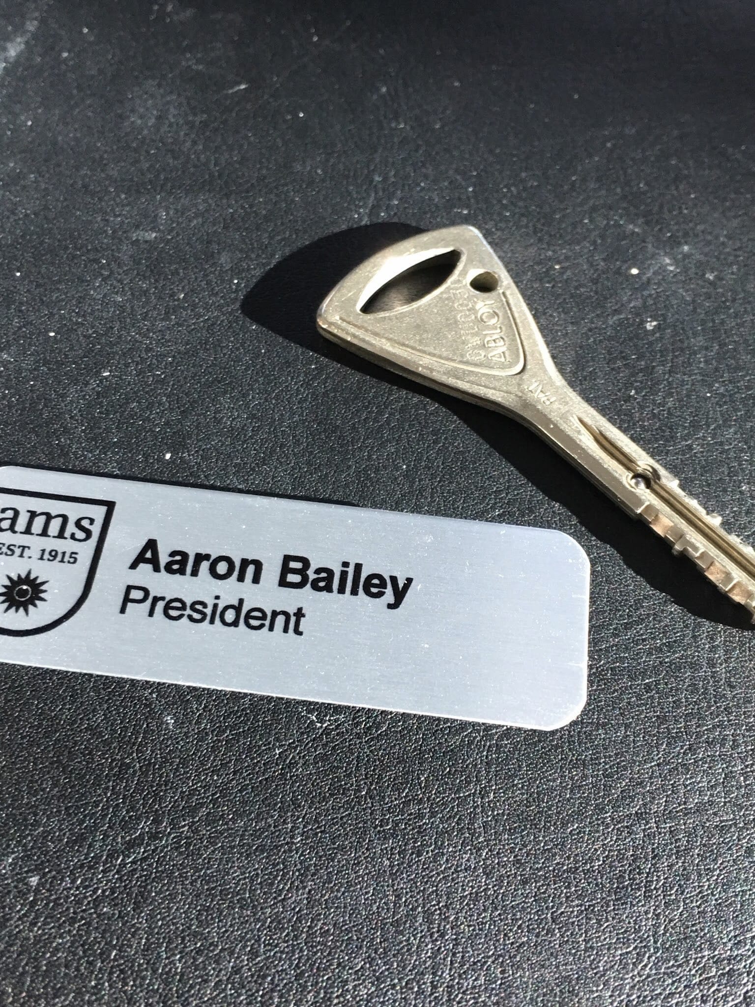 A key beside a name badge reading Aaron Bailey, President.
