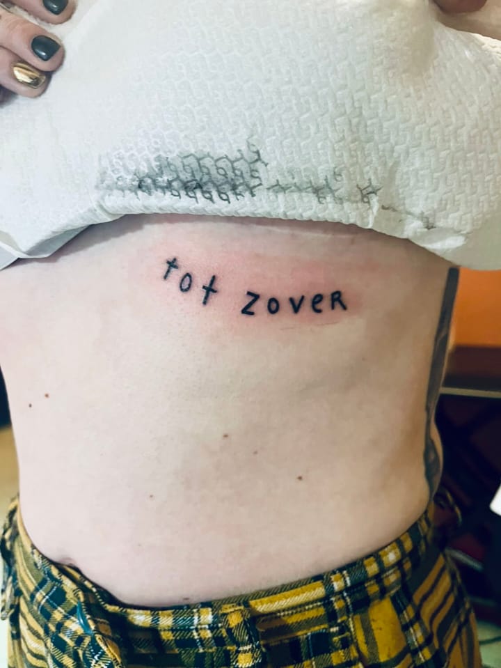 Photo of my text tattoo reading "tot zover" under my left breast.